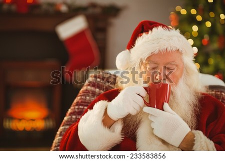 Father christmas drinking a hot beverage at home in the living room