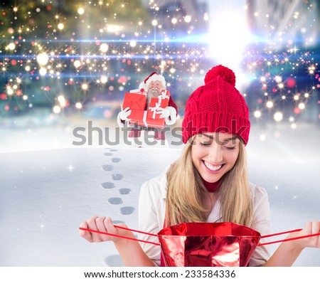 Pretty blonde opening gift bag against santa delivering gifts in city