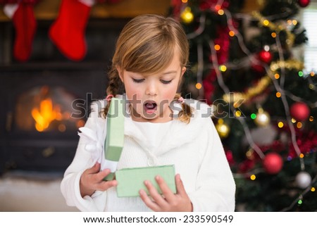 Shocked little girl opening a gift at home in the living room