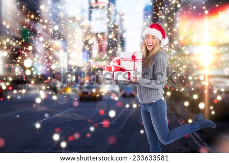 Festive blonde holding pile of gifts against blurry new york street