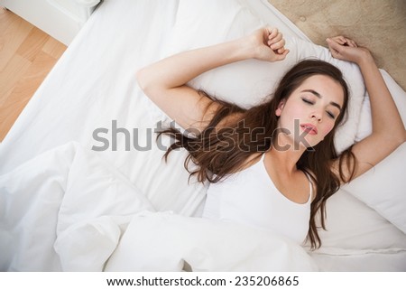 Pretty brunette waking up in bed at home in the bedroom