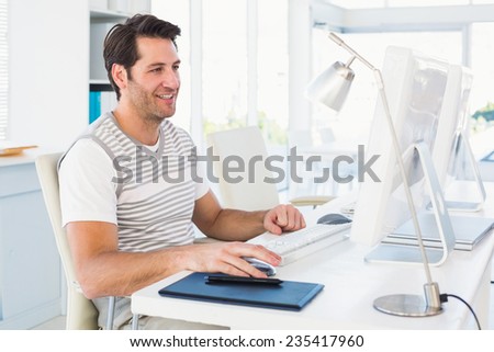 Smiling casual young man using computer in the office