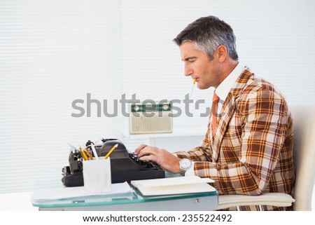 Retro man with cigarette typing on typewriter in his office