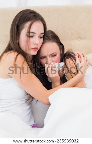 Brunette comforting her crying friend at home in the bedroom
