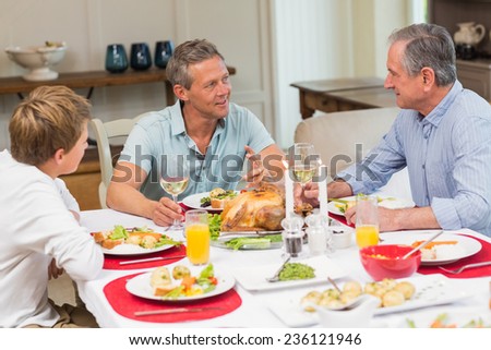 Grandfather, father and son speaking together at home in the living room