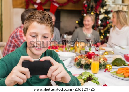 Young boy holding smartphone during christmas dinner at home in the living room