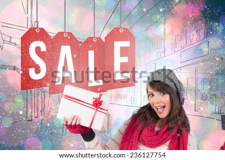 Brunette in winter clothes holding gift against light glowing dots on blue