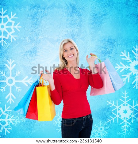 Happy blonde holding shopping bags against blue snow flake pattern design