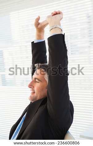 Peaceful businessman stretching his arms in his office