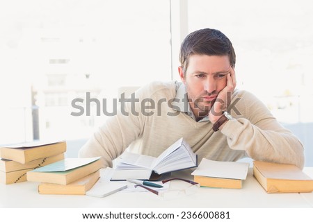 Bored casual businessman studying at his desk in his office
