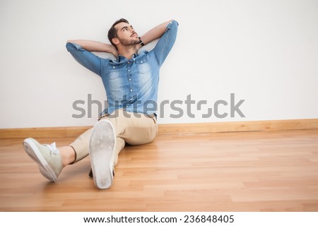 Casual man sitting on floor looking up at home in the living room