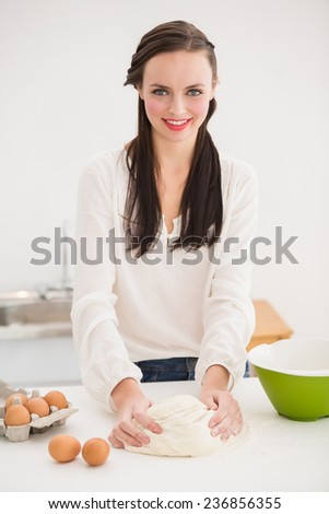 Pretty brunette making dough on counter at home in the living room