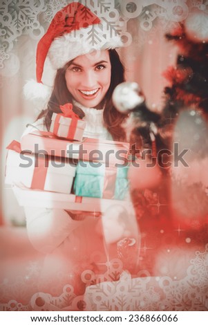 Festive brunette holding pile of gifts near a christmas tree against candle burning against festive background