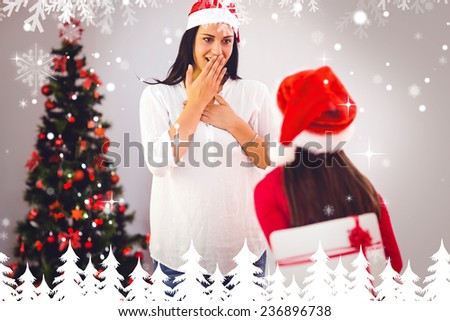 Daughter surprising her mother with christmas gift against fir tree forest and snowflakes