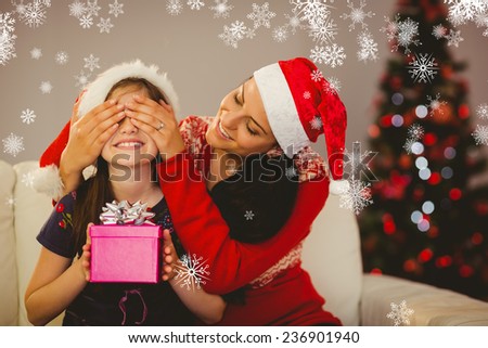 Mother surprising her daughter with christmas gift against snowflakes