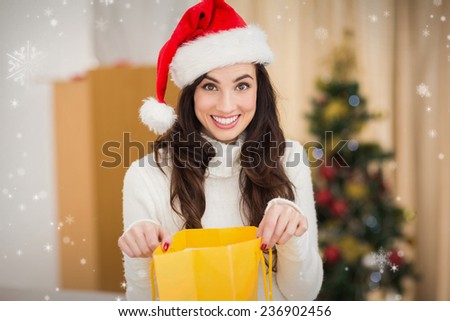 Festive brunette opening gift bag against snow falling