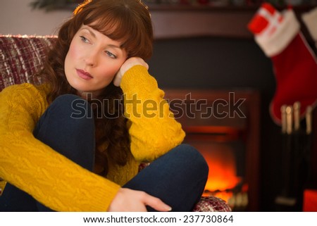 Pretty redhead in day dreaming at christmas at home in the living room