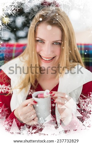 Smiling blonde in winter clothes holding mug against christmas theme frame in silver