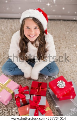Festive little girl smiling at camera with gifts against twinkling stars