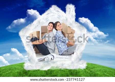 Beautiful couple sitting back-to-back against green field under blue sky