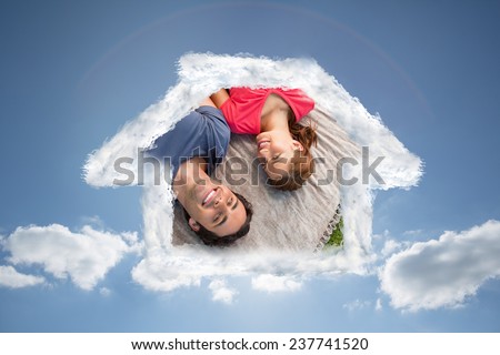 Two friends looking towards the sky while lying on a quilt against cloudy sky with sunshine