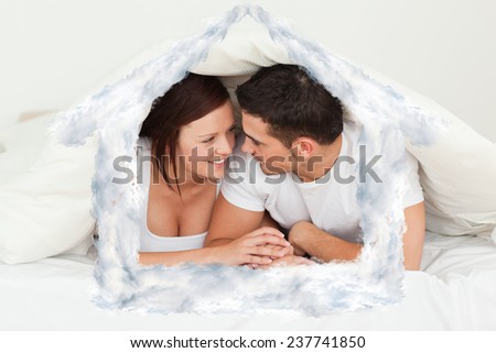 Happy couple hiding under a blanket against house outline in clouds