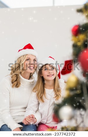 Festive mother and daughter smiling at tree against twinkling stars