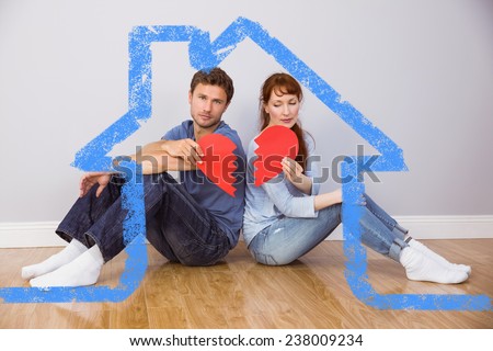 Couple holding a broken heart against house outline