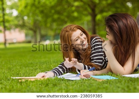 Cheerful female college students with books in the park