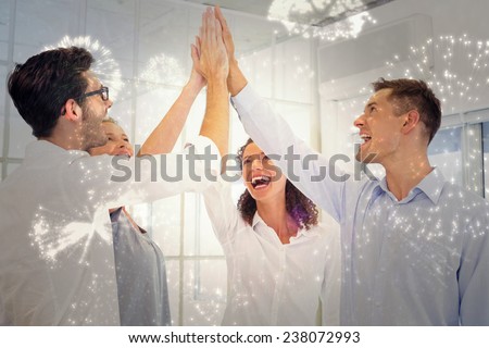 Casual business team high fiving against white fireworks exploding on black background