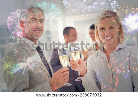 Business team celebrating with champagne and looking at camera against colourful fireworks exploding on black background