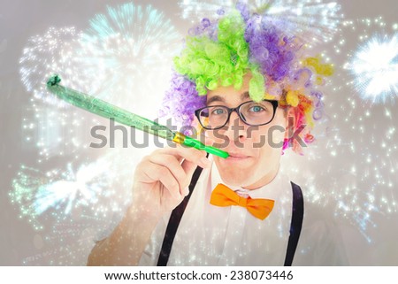 Geeky hipster wearing a rainbow wig blowing party horn against colourful fireworks exploding on black background