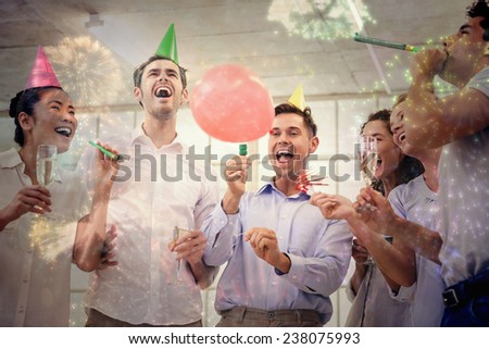 Casual business team celebrating with champagne and party horns against colourful fireworks exploding on black background