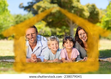 Family lying down in the park against house outline in clouds