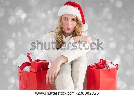 Serious woman sitting on floor with shopping bag against grey abstract light spot design