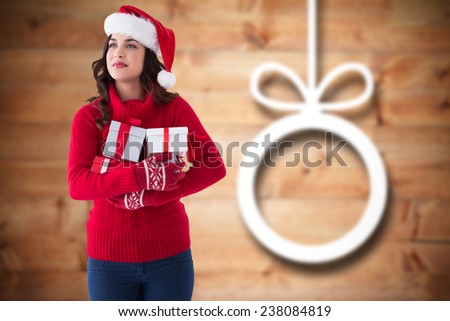 Thoughtful brunette holding many gifts against blurred christmas decorations on wood