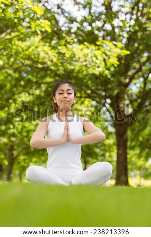 Full length of healthy and beautiful young woman sitting with joined hands at park