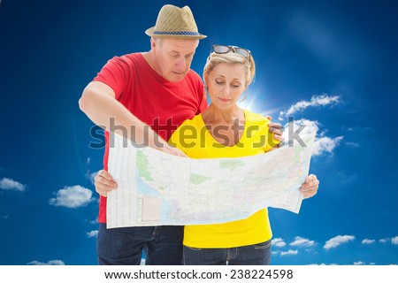 Lost tourist couple using map against cloudy sky with sunshine