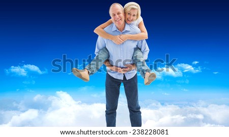 Mature man carrying his partner on his back against bright blue sky over clouds