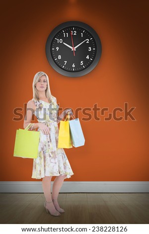 Elegant blonde with shopping bags against room with wooden floor