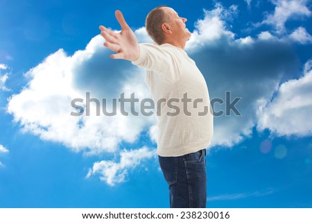 Happy mature man with hands out against cloudy sky