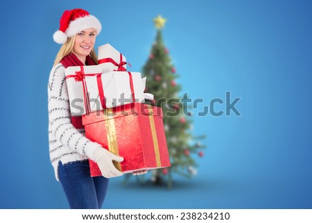 Festive blonde holding pile of gifts against blurry christmas tree