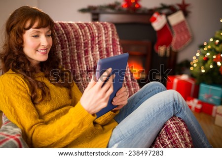 Redhead woman sitting on couch using tablet at christmas at home in the living room
