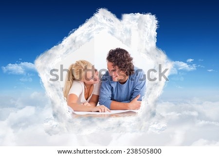 Smiling couple moving in a new house against bright blue sky over clouds