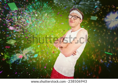 Geeky hipster posing in sportswear against colourful fireworks exploding on black background