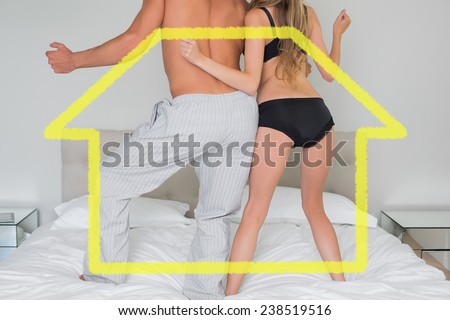 Low section of a semi dressed couple on bed against house outline