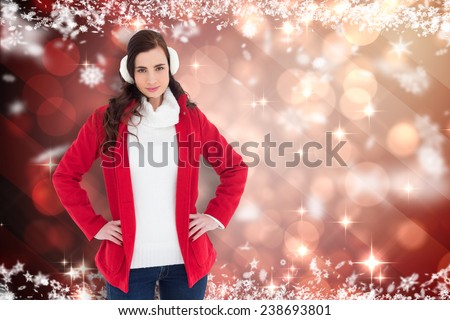 Smiling brunette posing with winter wear against light design shimmering on red