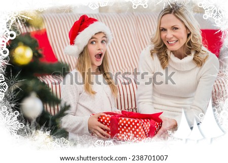Festive mother and daughter on the couch with gift against frost frame