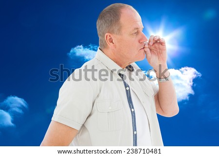 Older man holding hand to mouth for silence against bright blue sky with clouds