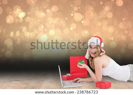Happy woman shopping online lying on the floor against shimmering light design over boards